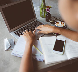 Overhead view of someone working at a desk with a laptop, notebook and smartphone