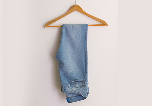 Light blue jeans hanging on a wooden hanger