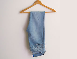 Light blue jeans hanging on a wooden hanger