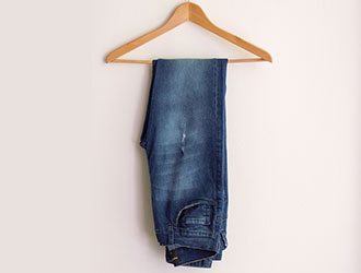 Dark blue jeans hanging on a wooden hanger