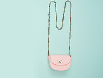 Small pink shoulder bag on a mint green background