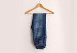 Dark blue jeans hanging on a wooden hanger