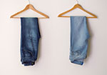 Two pairs of jeans hanging on wooden hangers