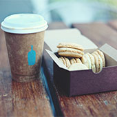 Takeaway coffee cup with macarons on a table