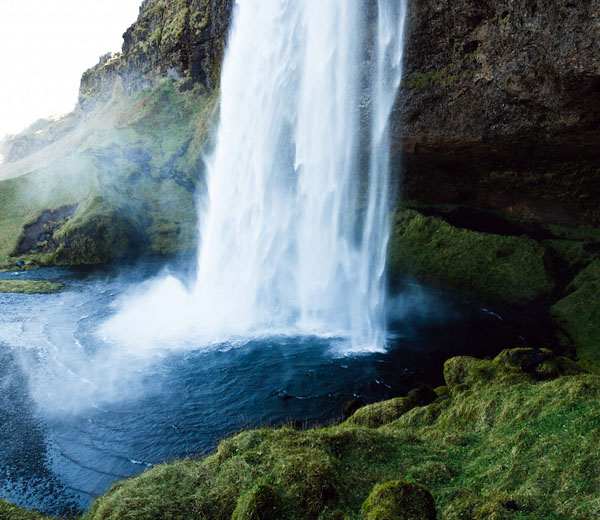 Waterfall cascading into a pool surrounded by moss-covered rock walls