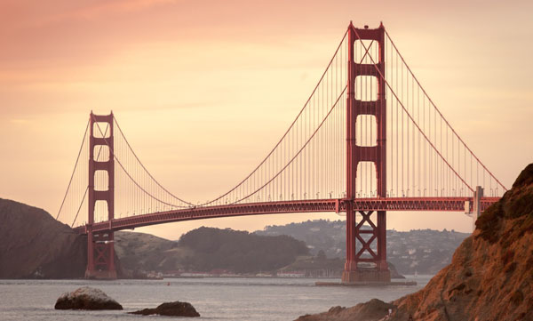 Golden Gate Bridge spanning the bay at sunset with orange sky