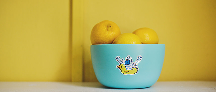 Bowl of fresh lemons on a yellow background