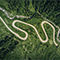 Aerial view of a winding road through green forest