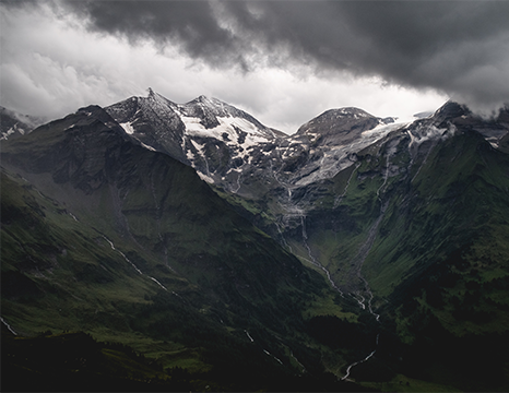 Snow-capped mountain range under cloudy sky