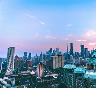 City skyline at dusk featuring tall buildings and a colorful sky with soft clouds in an urban setting.