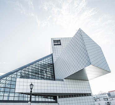 Modern architectural building with angular geometric shapes and a glass facade under a cloudy sky.