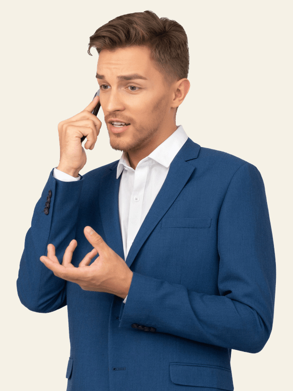 Young man in a blue suit expressing concern while talking on a mobile phone against a plain background