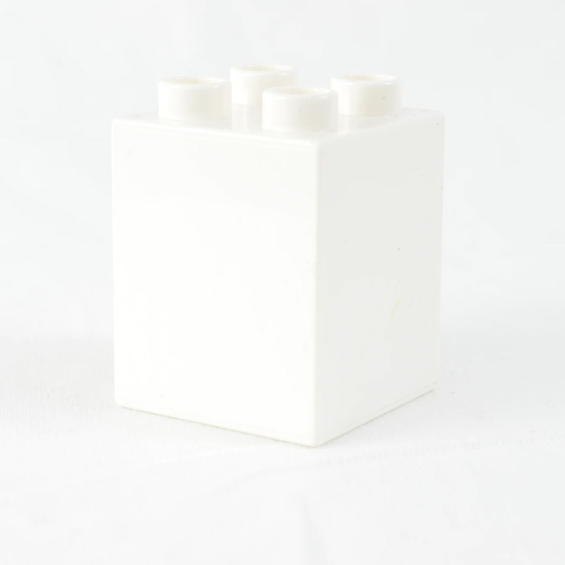 White plastic building block with four studs, resembling a toy construction brick, on a white background.
