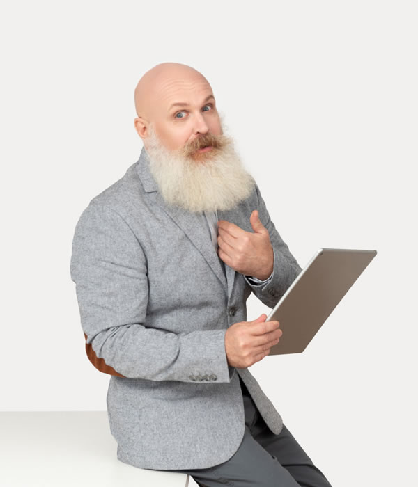 Man with a long white beard holding a tablet and looking surprised against a plain background.