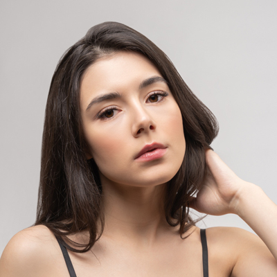 Studio portrait of a woman with long dark hair against a neutral background.