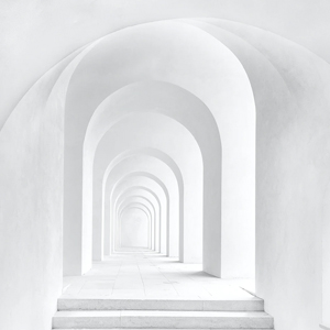White arched corridor with repeating arches creating a symmetrical, minimalist architectural walkway.