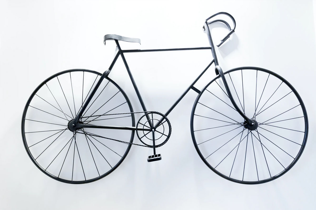 Minimalist black bicycle mounted against a white wall, viewed from the side.