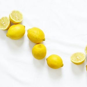 Fresh yellow lemons and lemon slices arranged on a white background.