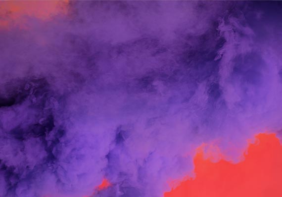 Dense swirling smoke in vibrant purple and red hues creating an abstract colorful cloud effect background.