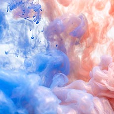 Swirling blue and pink ink blending together in a cloudy, abstract pattern suspended in liquid.
