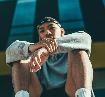 Person sitting casually on steps wearing a headband and sportswear
