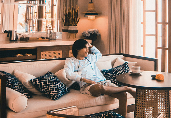 Person relaxing on a sofa in a stylish, well-lit living room with modern interior design and decor.
