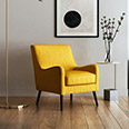 Yellow accent chair beside a small side table in a minimalist living room with wooden flooring.