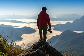 Image of man with camera on mountain peak