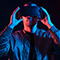 A person wearing a virtual reality headset, illuminated by dramatic blue and red lighting, appears engaged in an immersive digital experience.