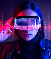 A person wearing futuristic VR goggles, immersed in a vibrant, digital world illuminated by colorful lights and patterns.